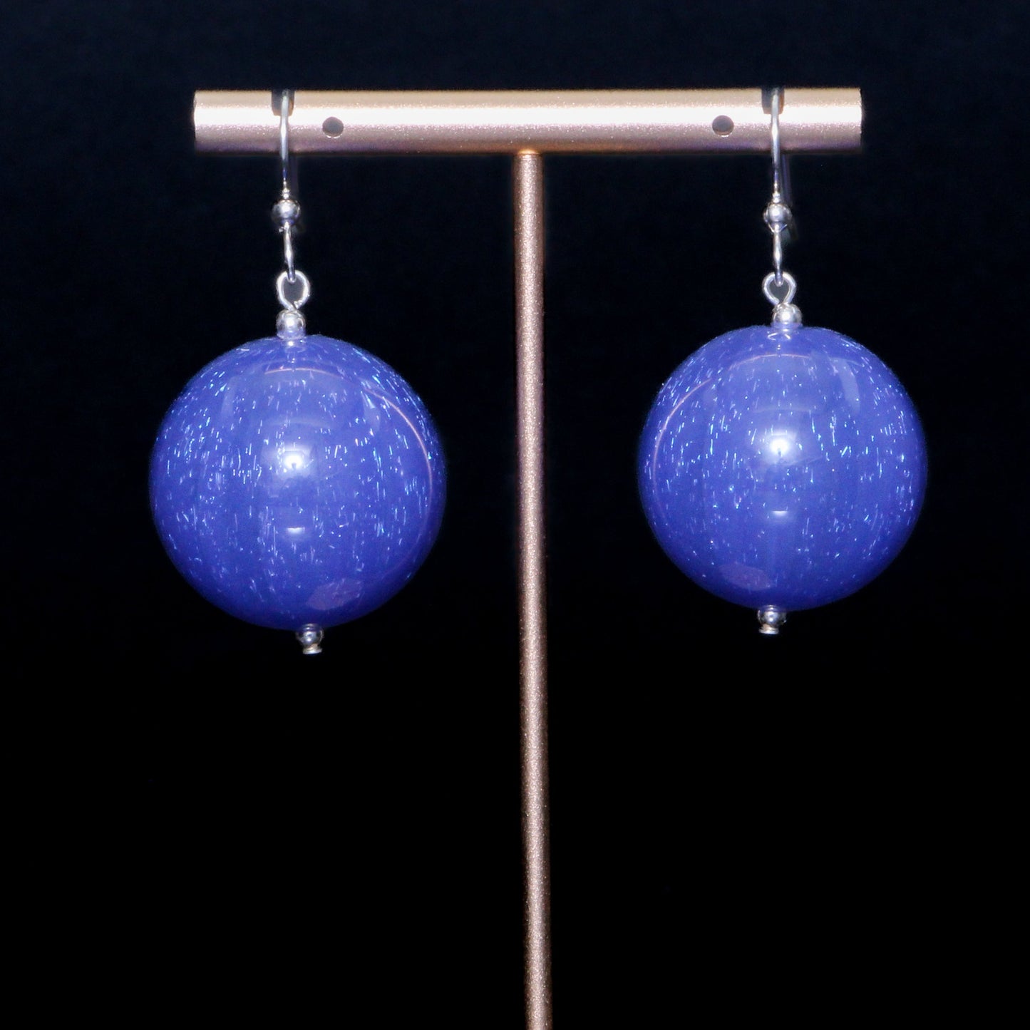 Blue handblown glass earrings against a black background