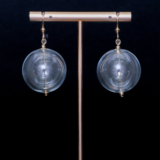 Clear handblown glass earrings against a black background