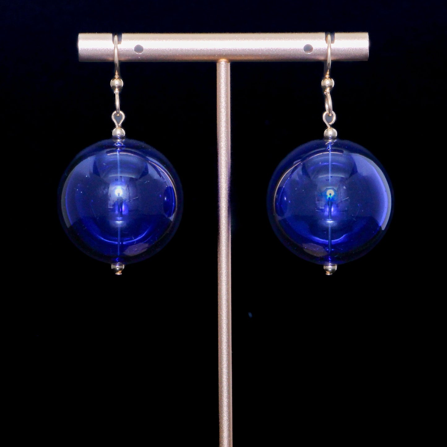 Cobalt blue handblown glass earrings against a black background