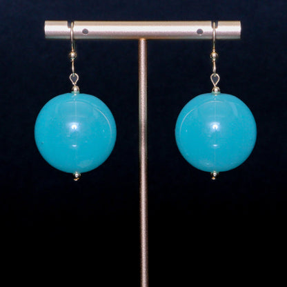 Turquoise handblown glass earrings against a black background
