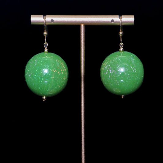 Green handblown glass earrings against a black background