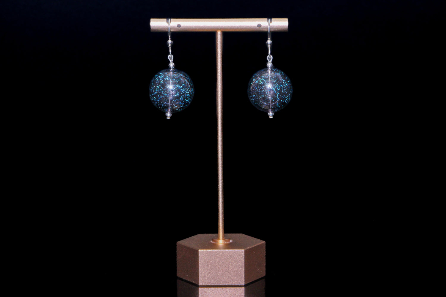 Sparkly black earrings on a black background