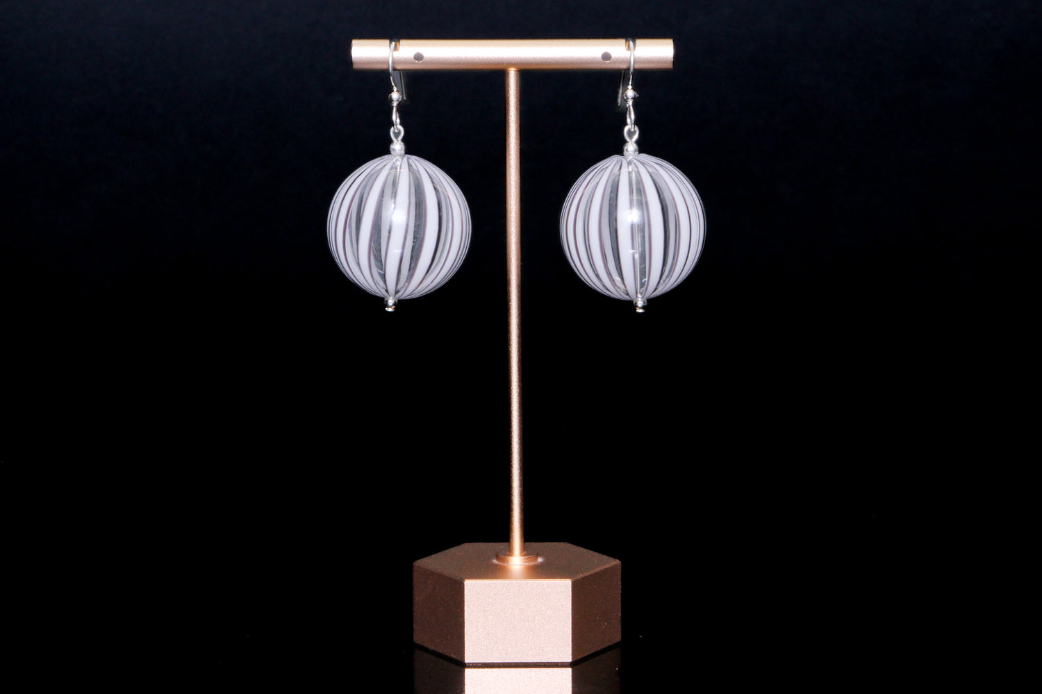 White and black glass earring on a black background