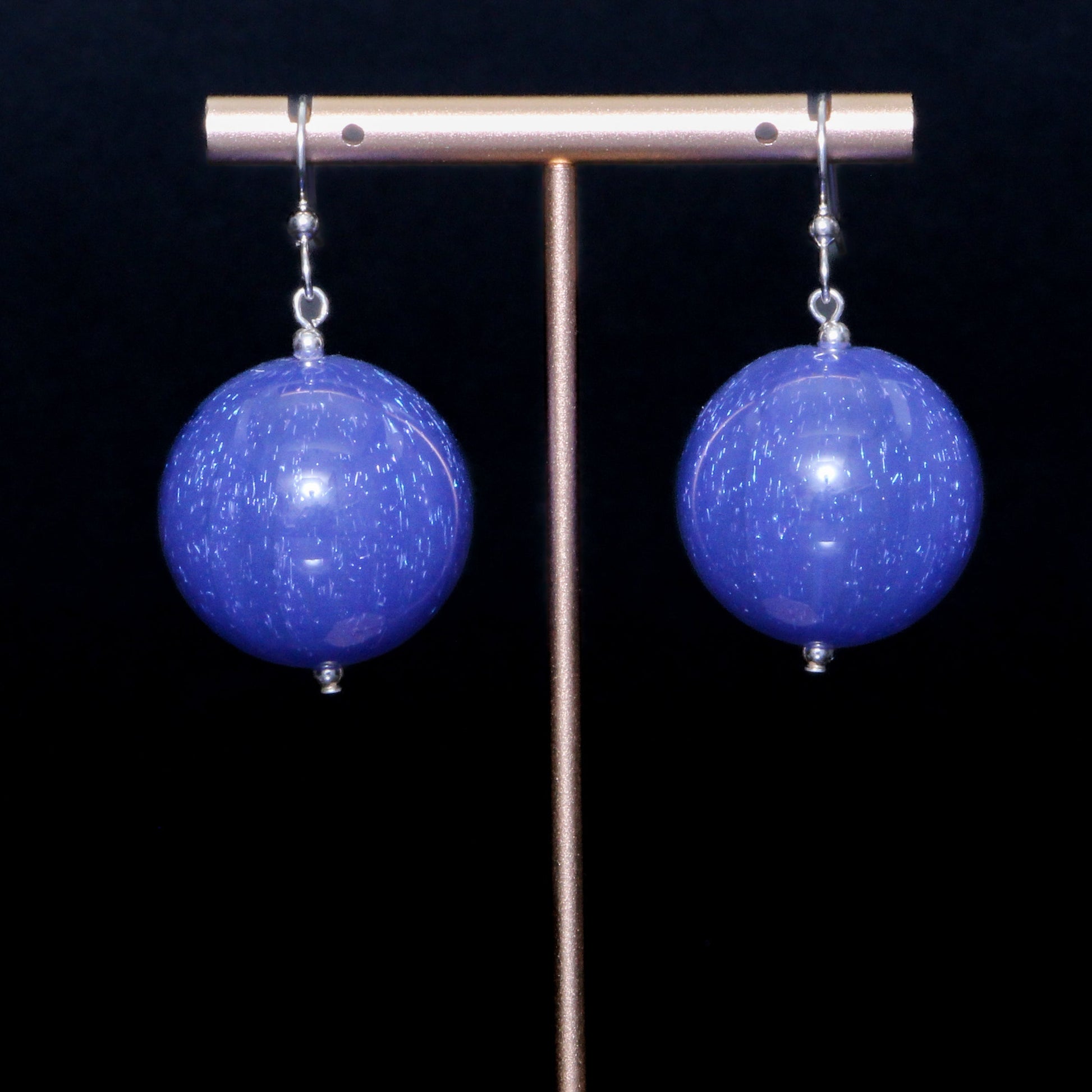 Blue handblown glass earrings against a black background