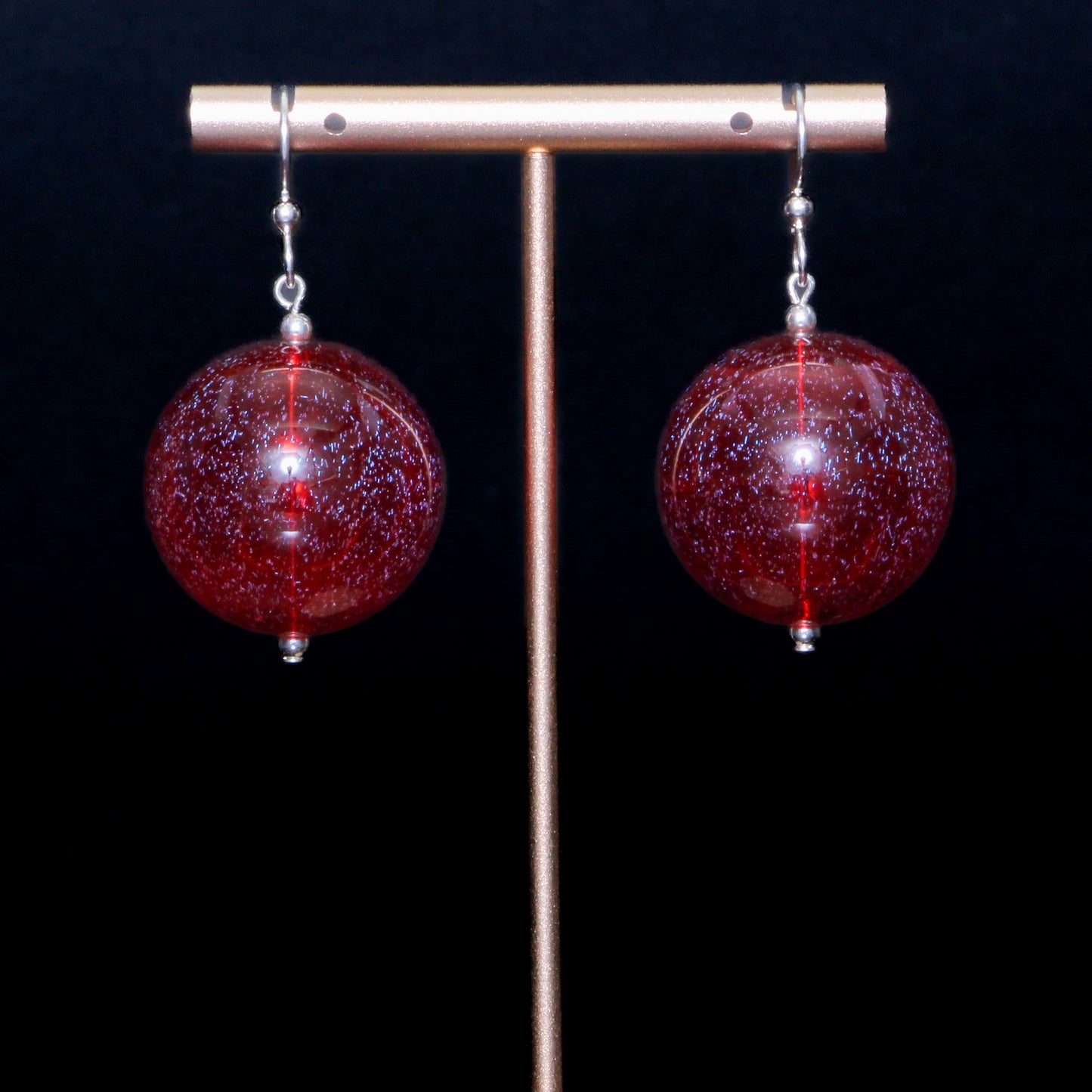 Red handblown glass earrings against a black background