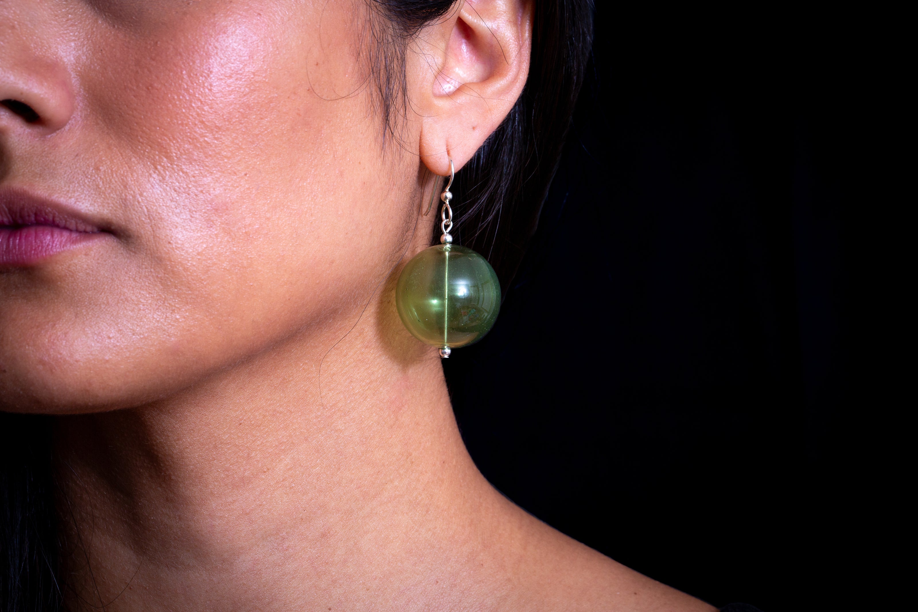 Woman wearing green handblown glass earrings